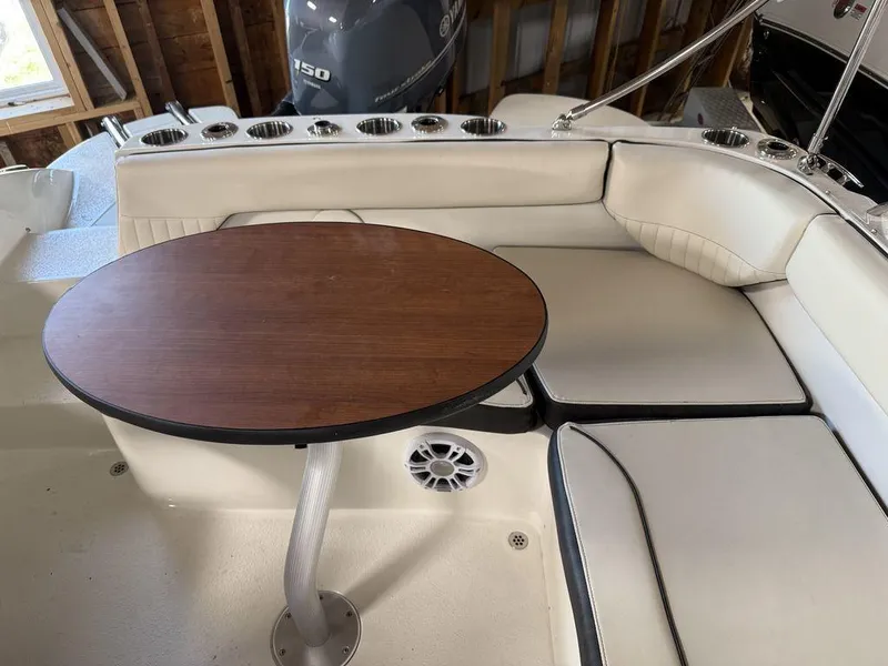 Slide: The Image of 2024 Stingray 192SC boat interior with cushioned seating and a wooden table. - 12