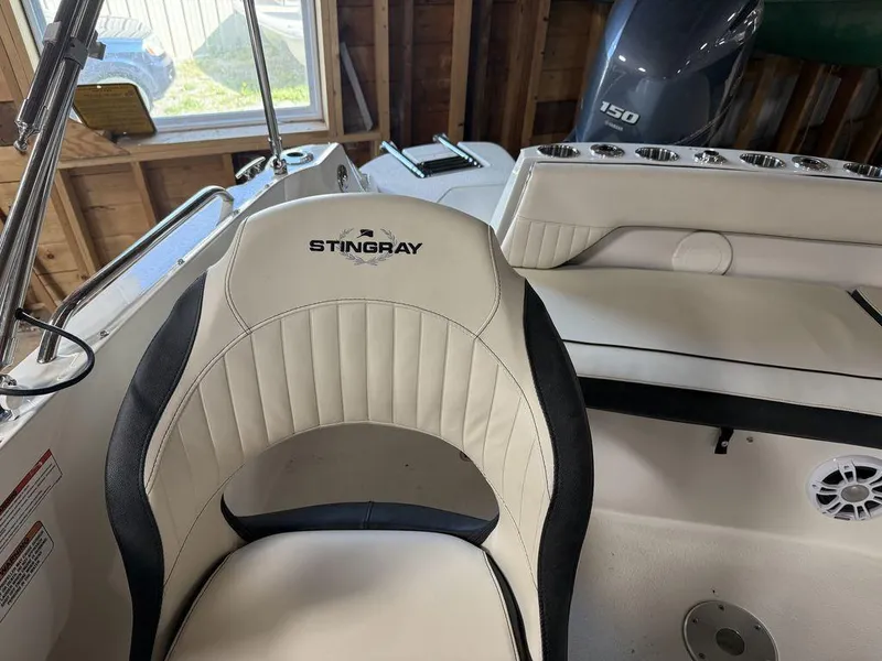Slide: The Image of 2024 Stingray 192SC boat interior with branded seating and motor in a garage setting. - 15