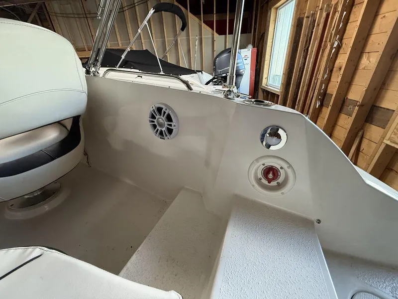 Slide: The Image of 2024 Stingray 192SC boat interior with seating and speaker in a wooden shed. - 8