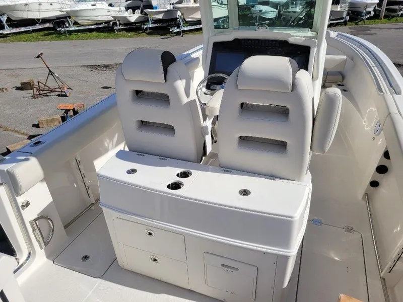 Slide: The Image of 2024 Sailfish 272 CC boat interior with dual captain's chairs and storage compartments. - 13