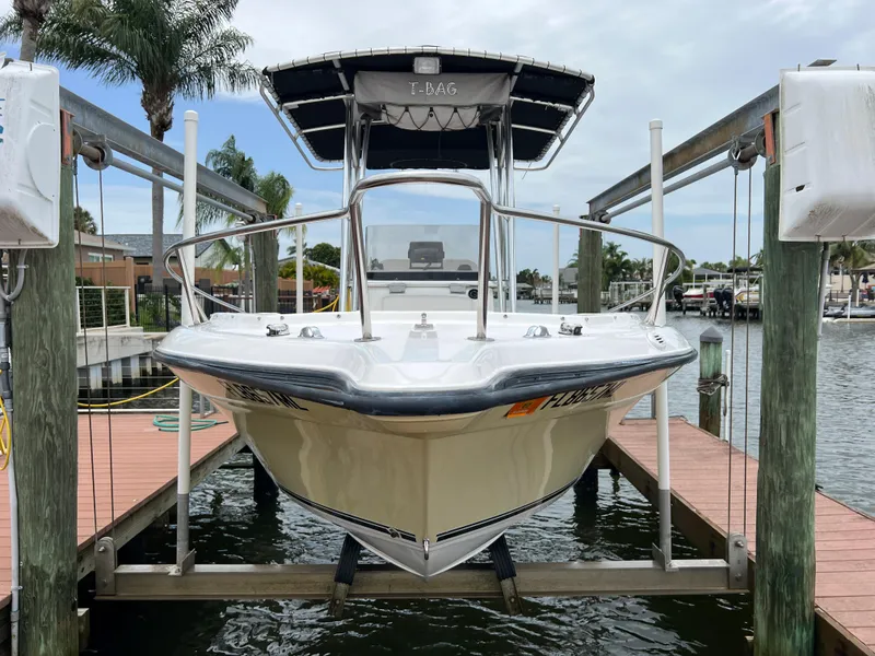 Slide: The Image of 2004 Century 2000 Center Console boat docked on lift, waterfront view. - 2