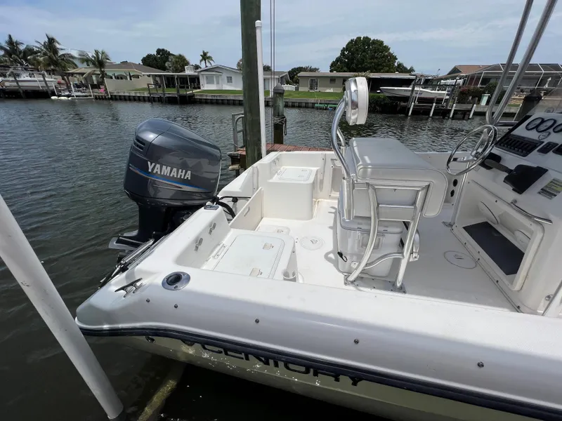 Slide: The Image of 2004 Century 2000 Center Console boat with Yamaha outboard motor docked by waterfront homes. - 4