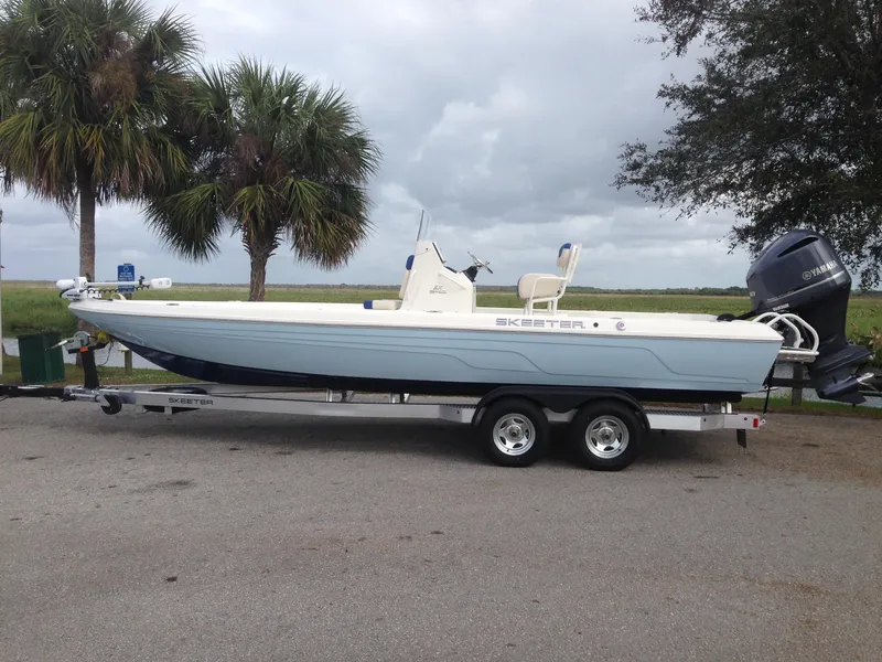 The Image of 2016 Skeeter 240SX boat on trailer with outboard motor, parked near palm trees. - 0