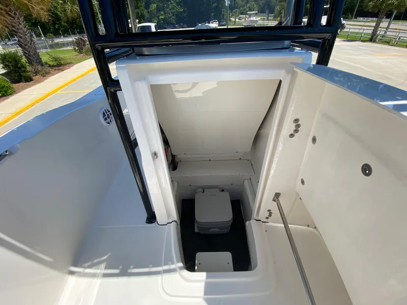 Slide: The Image of 2026 Robalo R200 Center Console boat interior with storage compartment and portable toilet. - 15