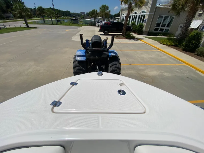 Slide: The Image of 2026 Robalo R200 Center Console boat on trailer, parked near a blue tractor. - 19