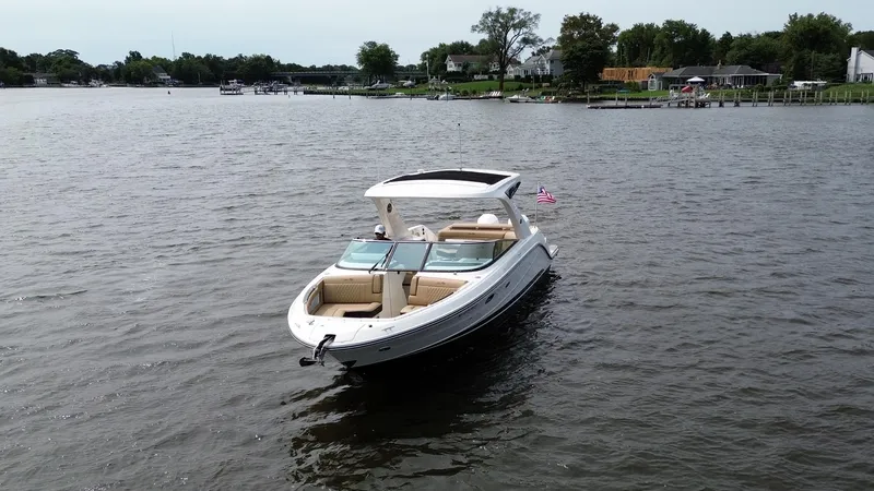 Slide: The Image of 2023 Sea Ray SLX 310 boat on a calm lake with shoreline in the background. - 3