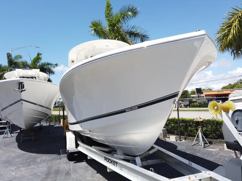 Slide: The Image of 2026 Regulator 28 boat on trailer, parked outdoors with palm trees in background. - 2