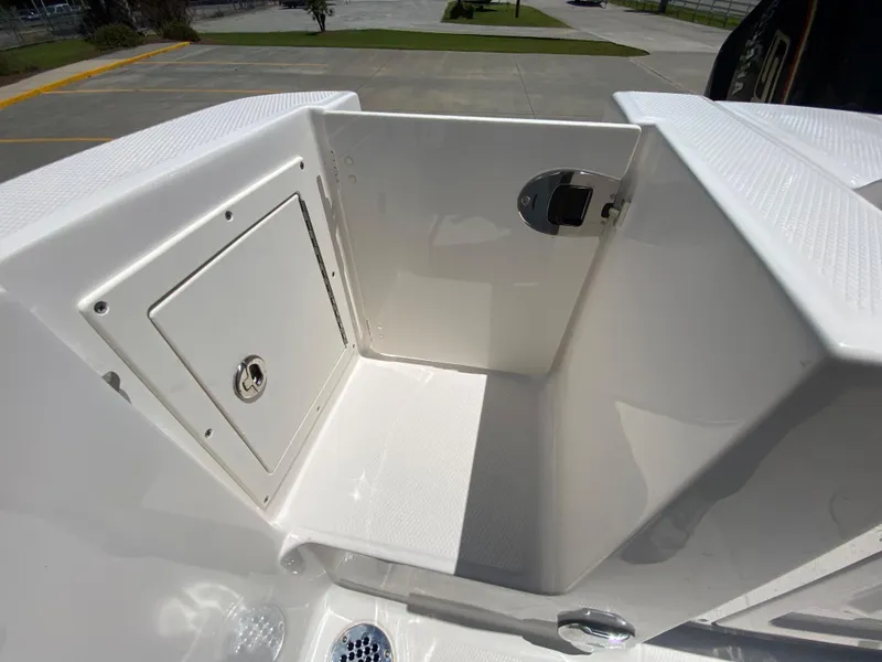 Slide: The Image of 2026 Robalo R230 Center Console boat storage compartment, white interior, outdoor setting. - 11