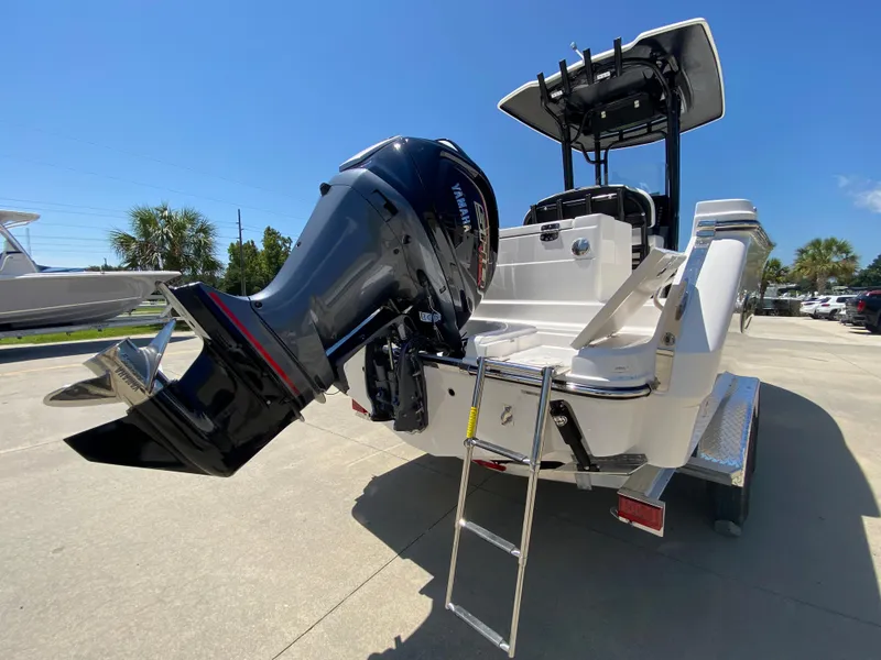 Slide: The Image of 2026 Robalo R230 Center Console boat with outboard motor and ladder, parked outdoors. - 5