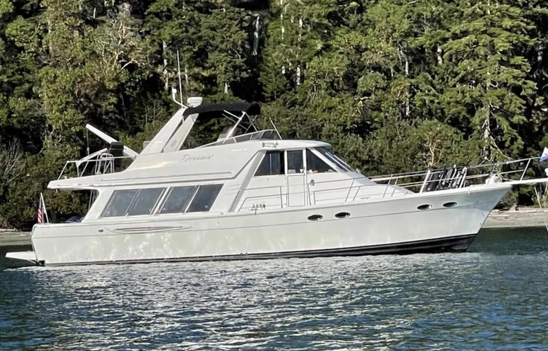 Slide: The Image of 2004 Meridian 490 Pilothouse yacht on calm water, surrounded by lush greenery. - 1