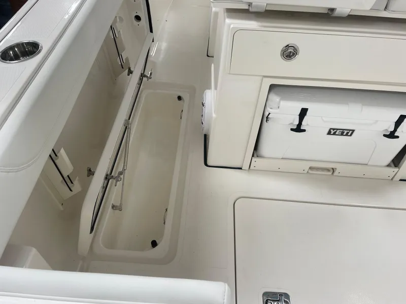 Slide: The Image of 2024 Pursuit S 248 Sport boat interior with storage compartments and Yeti cooler. - 16