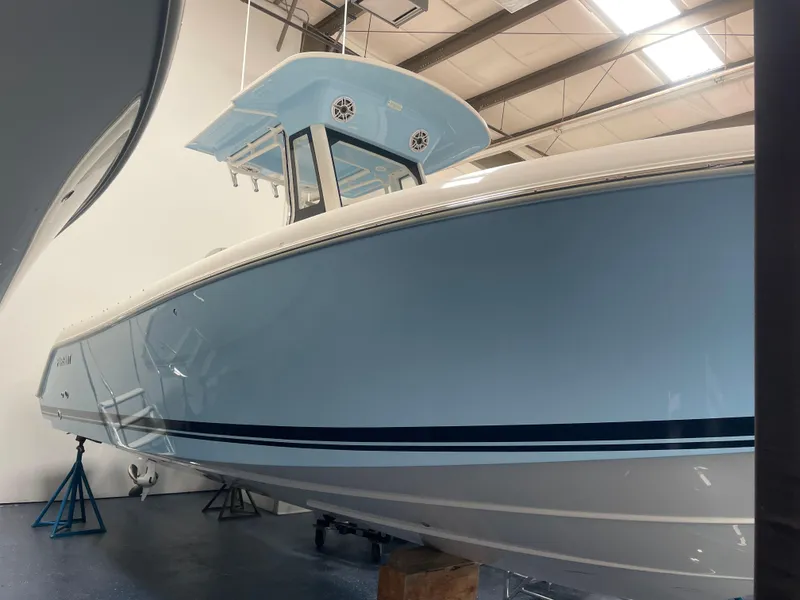 Slide: The Image of 2024 Pursuit S 248 Sport boat in a showroom, light blue hull. - 2
