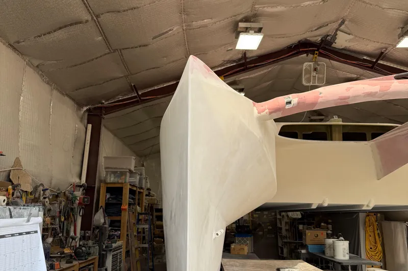 Slide: The Image of 2026 Schionning Arrow 1280 S catamaran under construction in a workshop. - 102