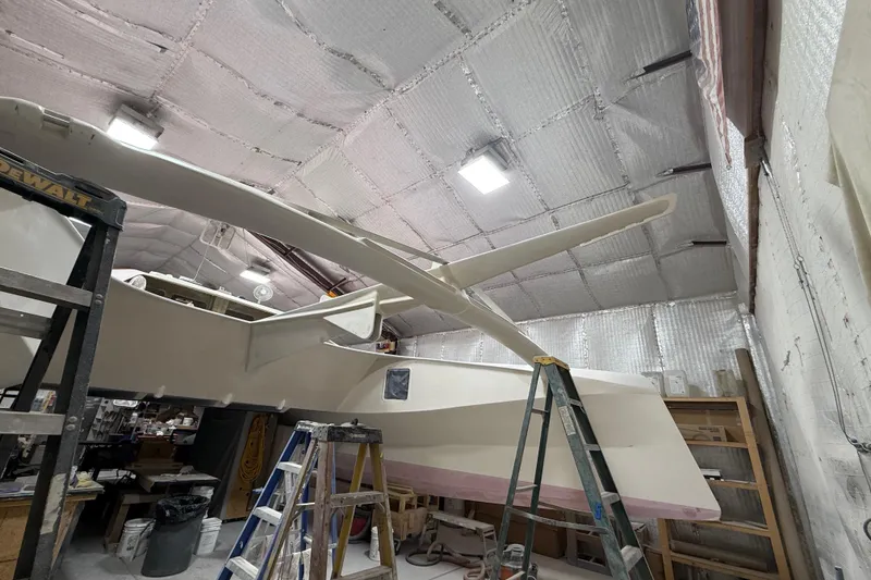 Slide: The Image of 2026 Schionning Arrow 1280 S catamaran under construction in a workshop. - 104