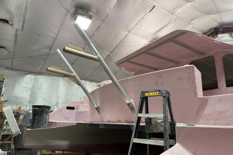 Slide: The Image of 2026 Schionning Arrow 1280 S catamaran under construction in a workshop. - 105