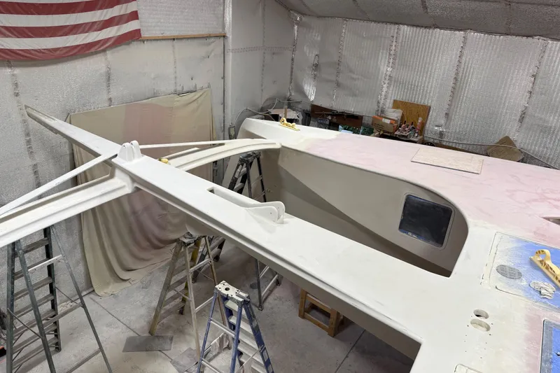 Slide: The Image of 2026 Schionning Arrow 1280 S catamaran under construction in a workshop. - 107