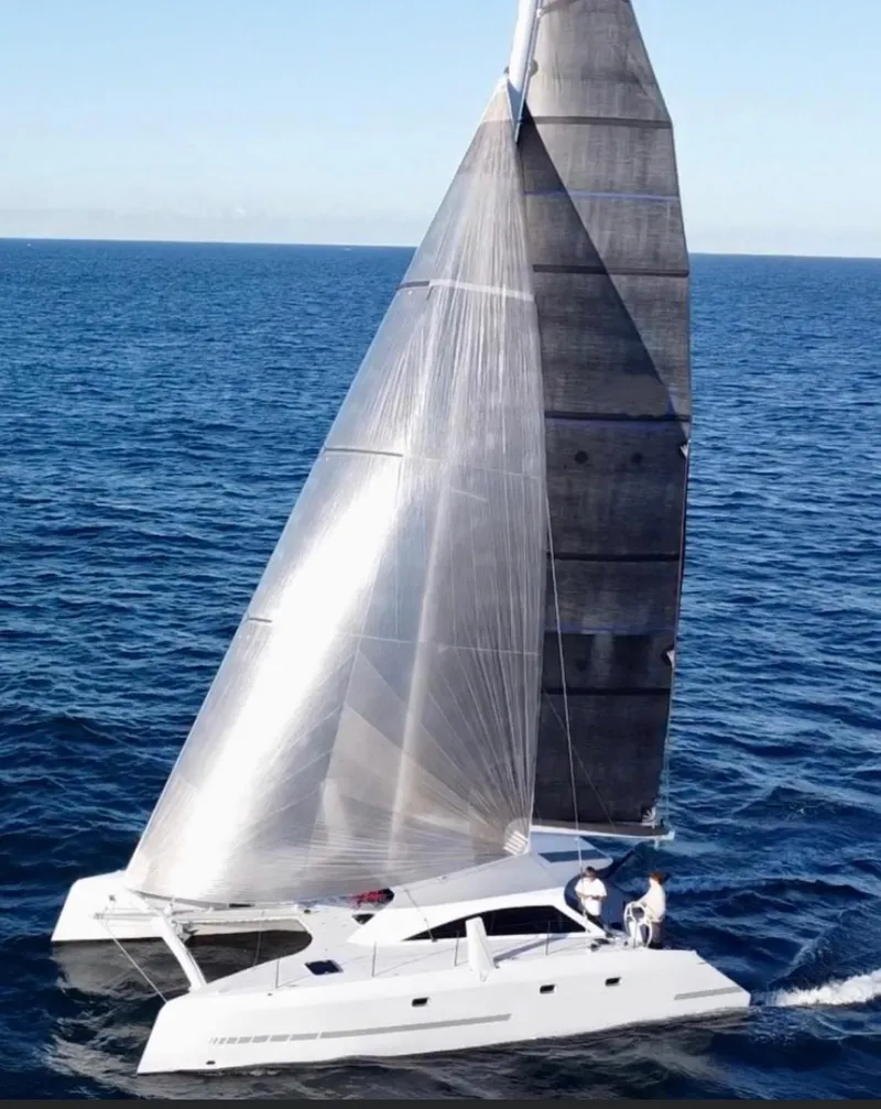 Slide: The Image of 2024 Schionning Arrow 1280 S catamaran docked by waterfront homes. - 2