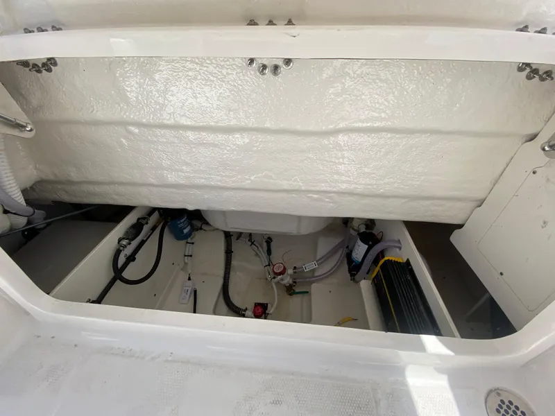 Slide: The Image of 2024 Robalo R230 Center Console boat storage compartment with visible wiring and components. - 10