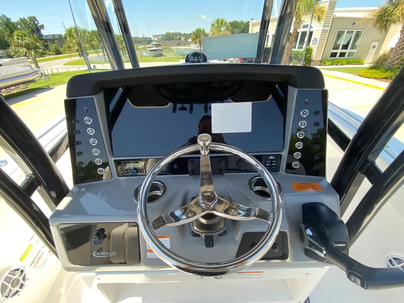 Slide: The Image of 2024 Robalo R230 Center Console boat helm with steering wheel and control panel. - 17