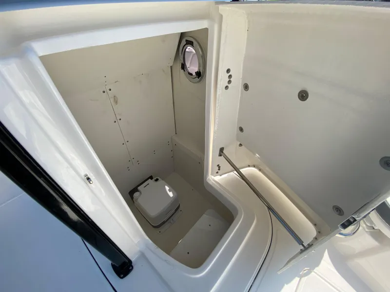 Slide: The Image of 2024 Robalo R230 Center Console boat interior with a compact marine toilet. - 24