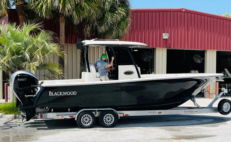 Slide: The Image of 2024 Blackwood 290 boat on trailer in front of red building. - 1