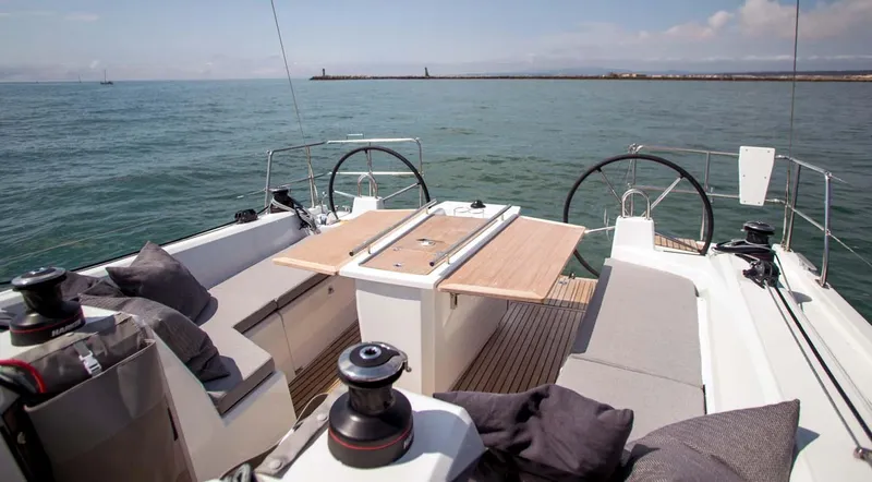 Slide: The Image of 2026 Beneteau Oceanis 40.1 yacht cockpit with dual steering wheels and seating, on calm sea. - 7