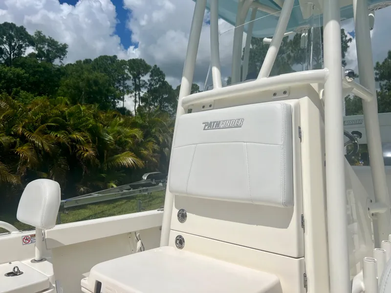 Slide: The Image of 2020 Pathfinder 2200 TRS boat interior with white seating and lush green background. - 12