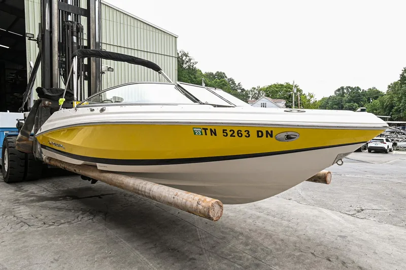 Slide: The Image of 2006 Regal 2000 Bowrider boat in yellow and white, docked on a forklift. - 2