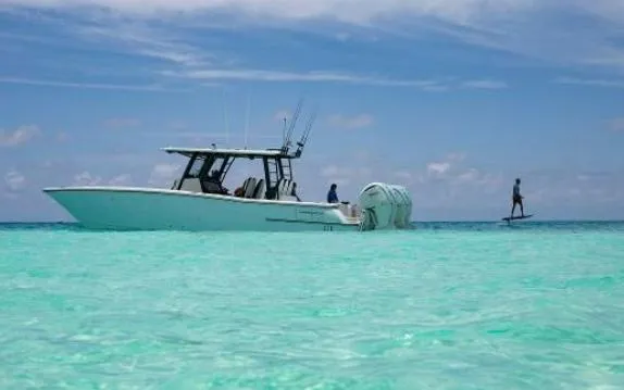 The Image of World Cat 400CC-X boat on turquoise water, 2022 model, with person paddleboarding nearby. - 0