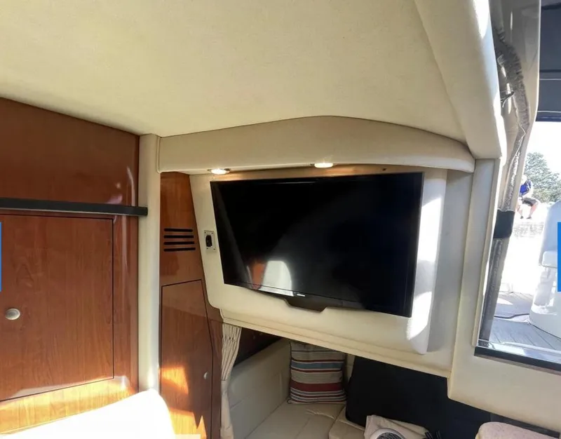 Slide: The Image of Interior of 2007 Sea Ray 320 Sundancer with mounted TV and wooden cabinetry. - 13