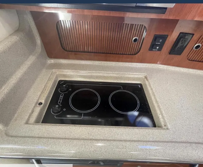 Slide: The Image of 2007 Sea Ray 320 Sundancer kitchen with electric stovetop and wooden cabinetry. - 15