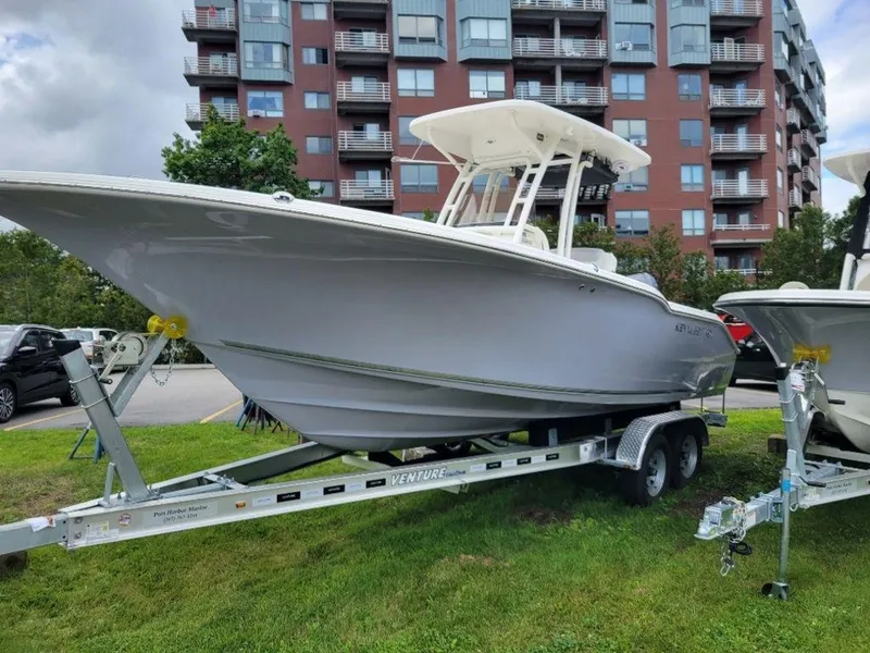 Slide: The Image of 2024 Key West 244 CC boat on trailer, parked on grass near modern apartment buildings. - 5