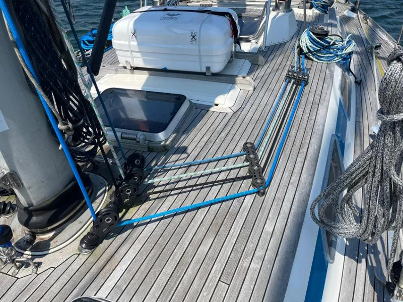 Slide: The Image of 1986 Nautor Swan 43 sailboat deck with ropes and equipment, showcasing teak wood finish. - 12