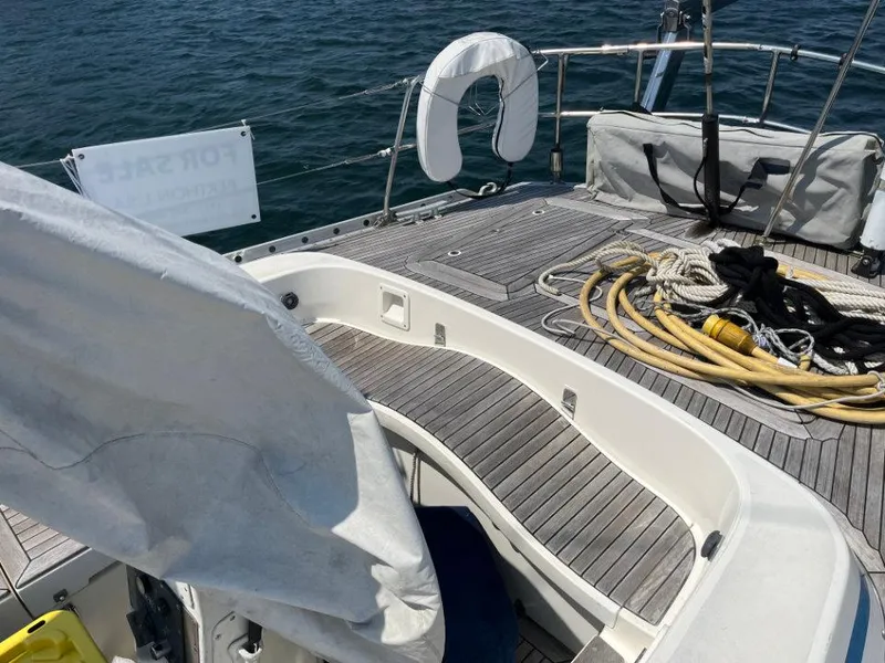 Slide: The Image of Nautor Swan 43 sailboat deck, 1986 model, with ropes and life preserver, on calm water. - 18