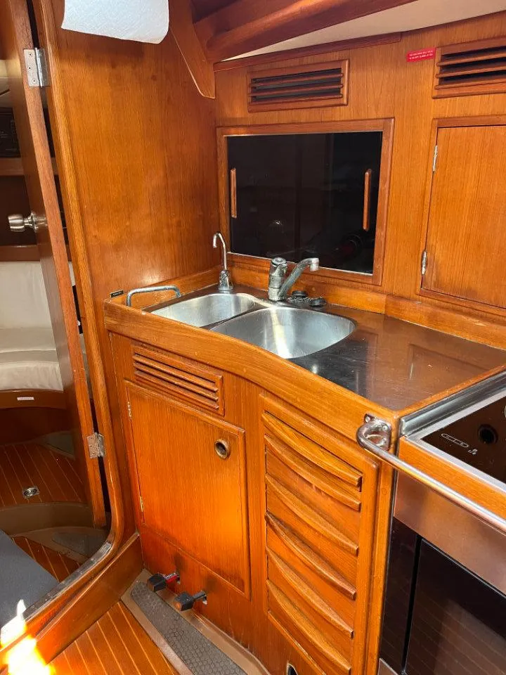 Slide: The Image of Nautor Swan 43 yacht kitchen interior, featuring wooden cabinetry and stainless steel sink, 1986 model. - 26