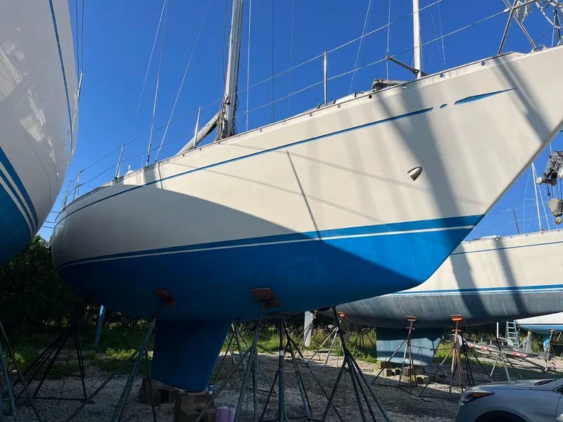 Slide: The Image of 1986 Nautor Swan 43 sailboat on stands, blue and white hull, clear sky background. - 34