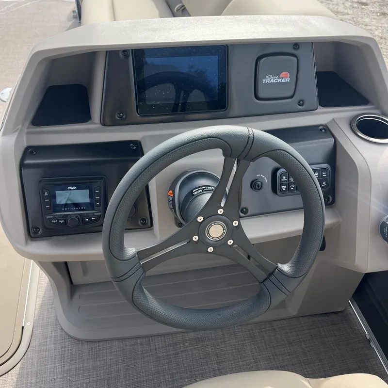 Slide: The Image of 2024 Sun Tracker Party Barge 22 XP3 dashboard with steering wheel and control panel. - 2