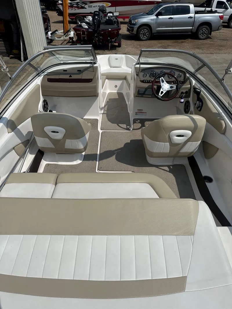 Slide: The Image of 2015 Regal 1900 boat interior with beige and white seating, dashboard, and steering wheel. - 21