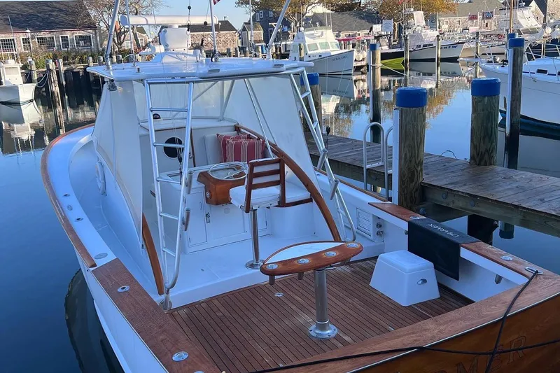 Slide: The Image of 1985 Rybovich Walkaround boat docked at a marina, featuring a wooden deck and fishing chair. - 4