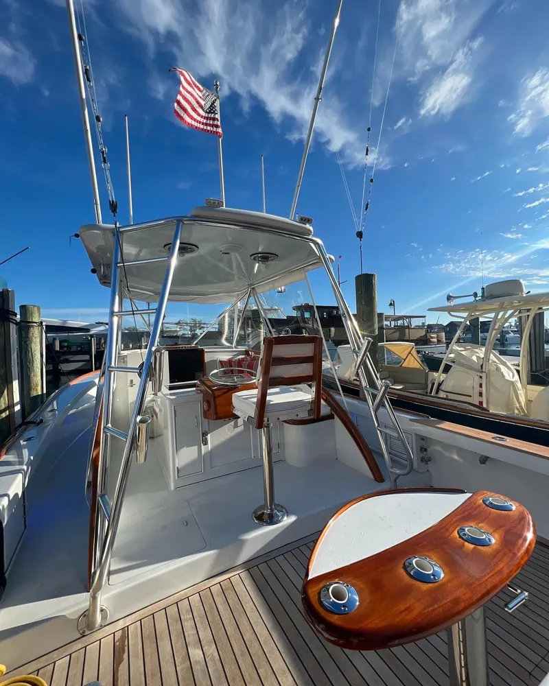 Slide: The Image of 1985 Rybovich Walkaround boat with American flag, docked under clear blue sky. - 5