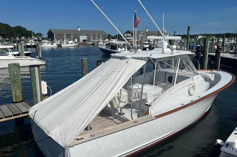 Slide: The Image of 1985 Rybovich Walkaround boat docked at a marina with a white canopy. - 9