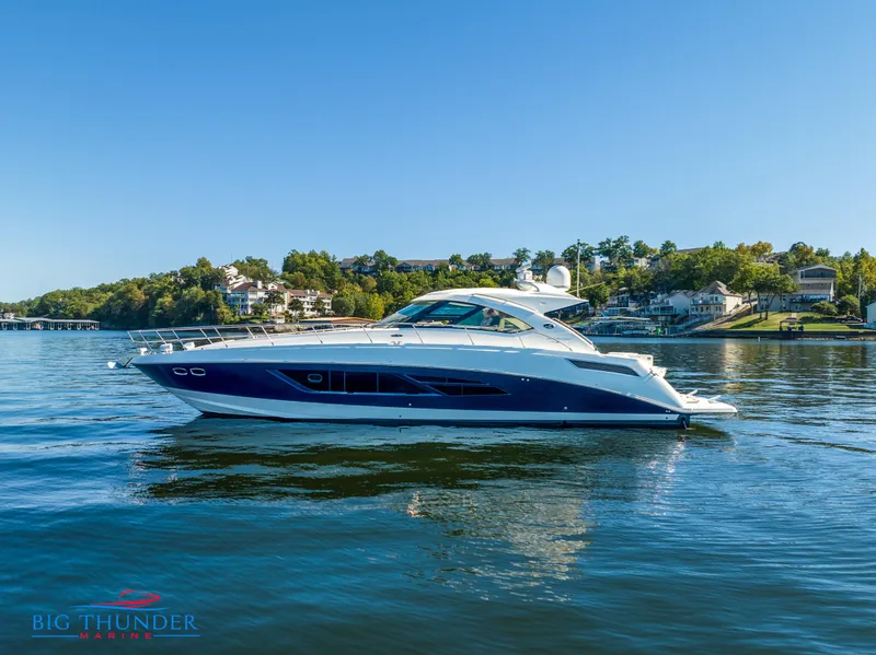 Slide: The Image of 2013 Sea Ray 540 Sundancer yacht on a serene lake with clear blue skies. - 1