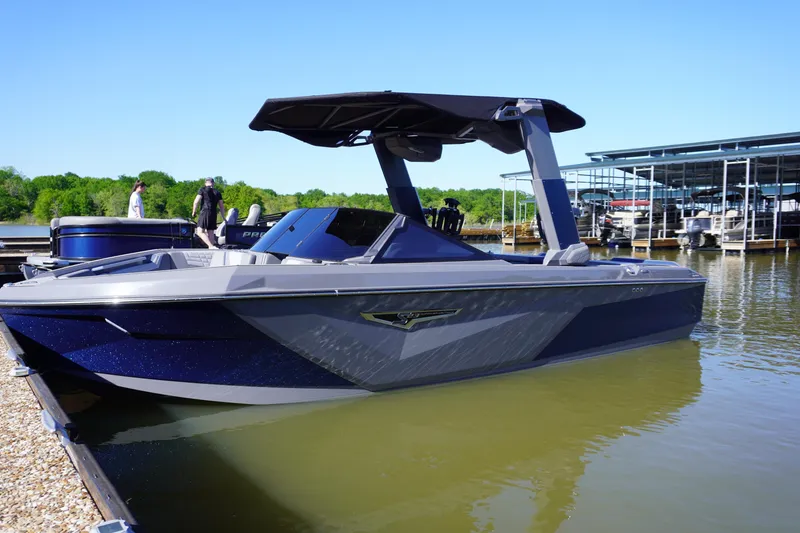 Slide: The Image of 2024 Nautique S23 boat docked on calm water, featuring sleek design and modern canopy. - 1