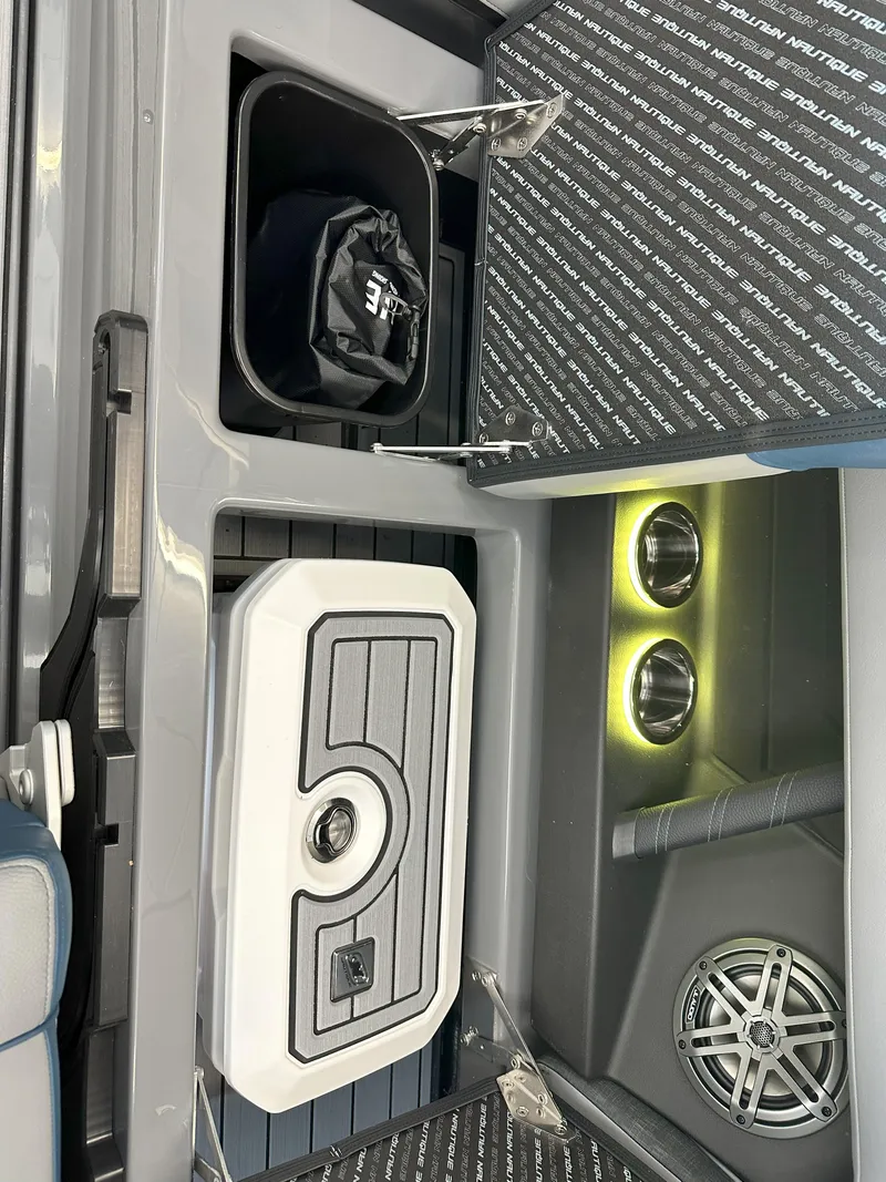 Slide: The Image of 2024 Nautique S23 boat interior with storage compartments, cup holders, and speaker. - 21