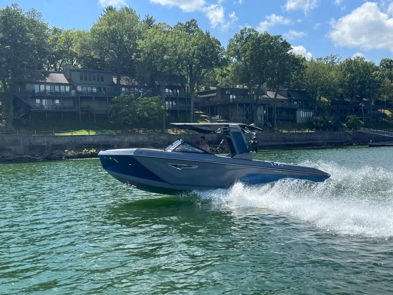 Slide: The Image of 2024 Nautique S23 boat cruising on a lake with waterfront homes in the background. - 3