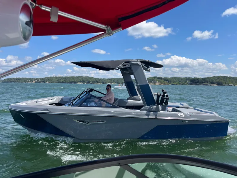Slide: The Image of 2024 Nautique S23 boat cruising on a lake under a clear blue sky. - 4