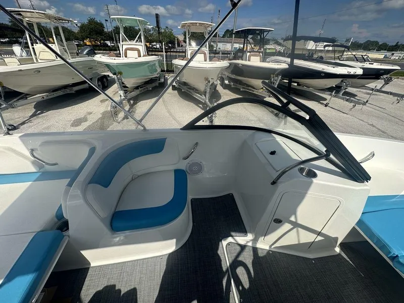 Slide: The Image of 2024 Bayliner Element E21 boat interior with blue and white seating, docked among other boats. - 2