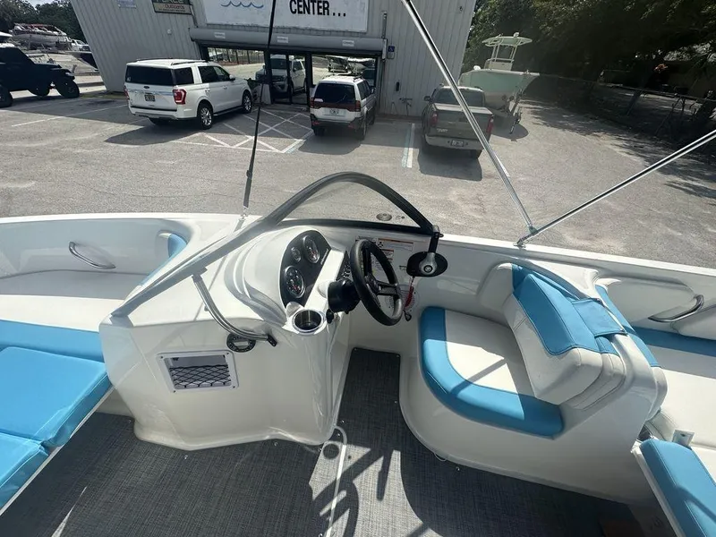 Slide: The Image of 2024 Bayliner Element E21 boat interior with blue and white seating, steering console, and dashboard. - 21