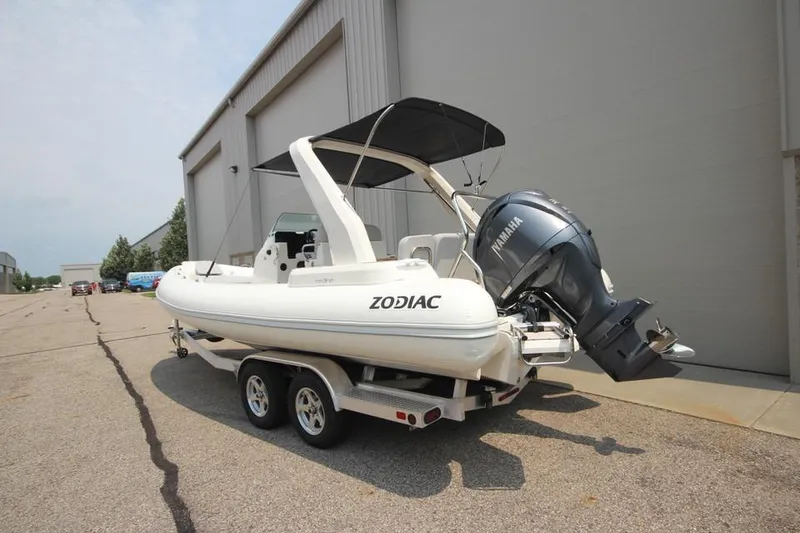 Slide: The Image of 2024 Zodiac Medline 7.5 NEO 300hp boat on trailer, parked outside a warehouse. - 6
