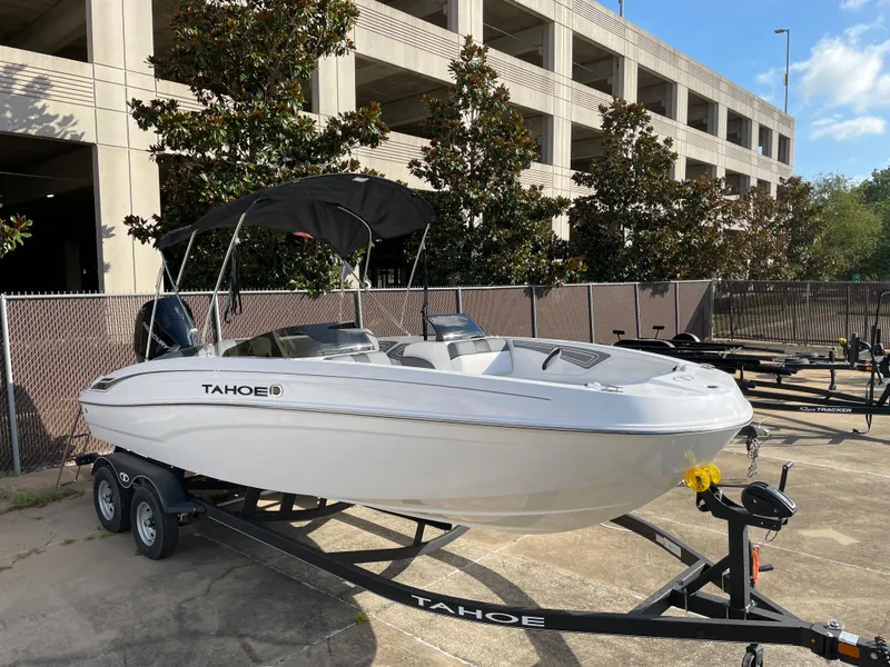 Slide: The Image of 2024 Tahoe T21 boat on trailer, parked outdoors near a building. - 2